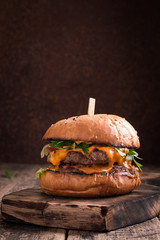 Tasty grilled burger with lettuce and mayonnaise ,on a rustic wooden table