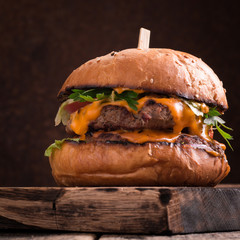 Tasty grilled burger with lettuce and mayonnaise ,on a rustic wooden table