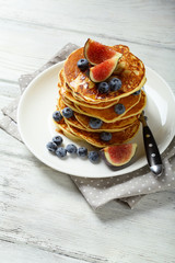 Pancakes with fruits on white wood