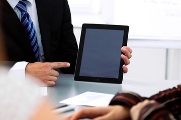 Group of business people at meeting, close up. Boss pointing into tablet computer monitor