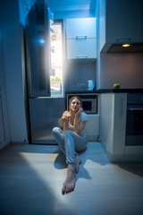 Fototapeta na wymiar Sleepy woman sitting on floor at open fridge at late night