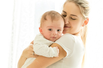 Closeup portrait of beautiful young mother cuddling her 3 months