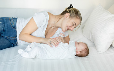 Smiling mother playing on bed with her cute baby boy