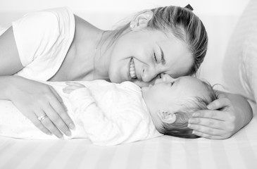 Black and white portrait of cheerful mother hugging and kissing