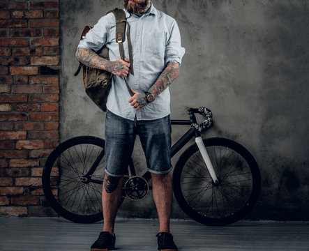 Portrait of bearded hipster male with bag and bicycle.