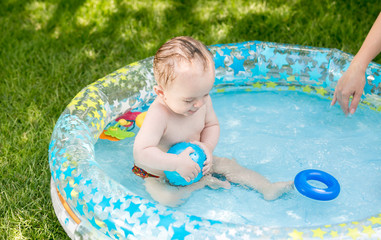 9 months old baby boy playing with ball in pool at garden