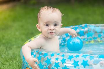 Fototapeta na wymiar Cute baby boy relaxing in pool at garden