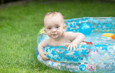 Fototapeta na wymiar Adorable baby boy swimming in the inflatable swimming pool at ga