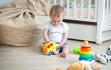 10 months old baby boy sitting on floor with colorful toy car