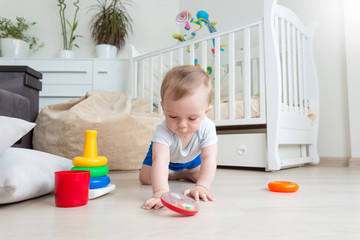 Adorable baby playing on floor with colorful rings from toy pyra