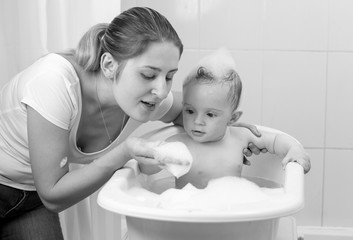 Black and white portrait of mother playing with baby in bath