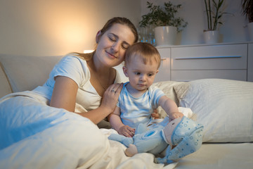 Fototapeta na wymiar Portrait of young mother lying in bed with her baby boy at night