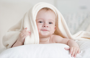 Fototapeta na wymiar Cute baby boy lying under white blanket on bed