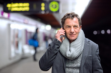 Senior man at the underground platform, talking on phone