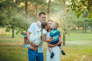 Happy young family on a background of water in the park, parents hold children  hands