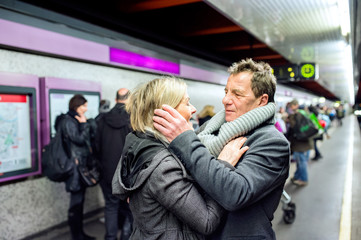 Senior couple standing at the underground platform, hugging