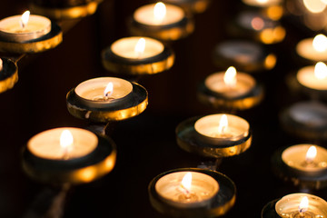 Rows of candles in a church that have been lit bu worshippers and churchgoers in remembrance of...