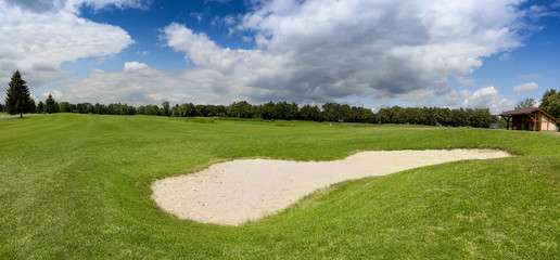 Sand bunker on golf course with perfect green grass