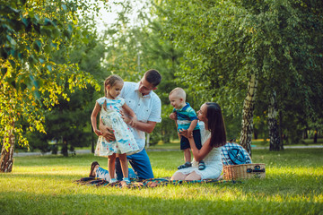 Young happy family of four on picnic in the park