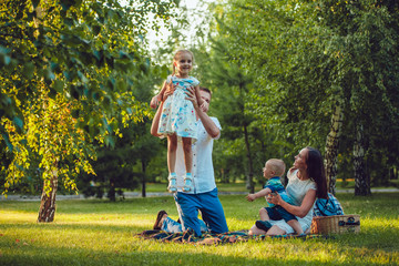 Young happy family of four on picnic in the park