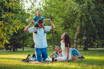 Young happy family of four on picnic in the park