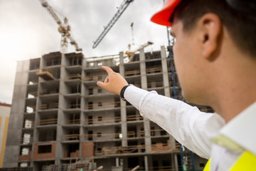 Closeup of construction engineer pointing with hand at building
