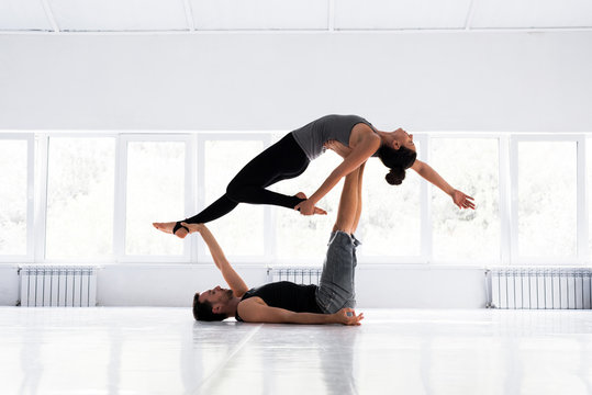 Couple practicing acro yoga in white studio. Acro yoga concept.