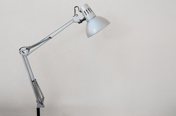 Desk lamp with white concrete wall as background, it can be used for presentations