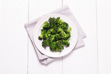 Bunch of fresh green broccoli on brown plate over wooden background