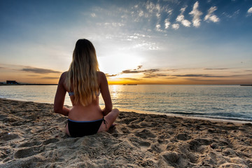 Fototapeta na wymiar attractive sexy woman in bikini siting on sand on lonely beach on sunset sunrise