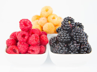 Raspberries and blackberries: bowls of fruit on white background