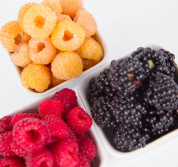 Raspberries and blackberries: bowls of fruit on white background
