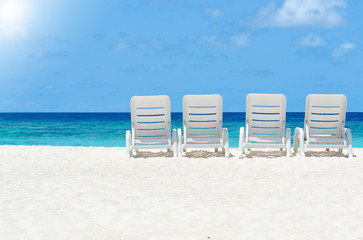white beach chairs in sand at ocean front