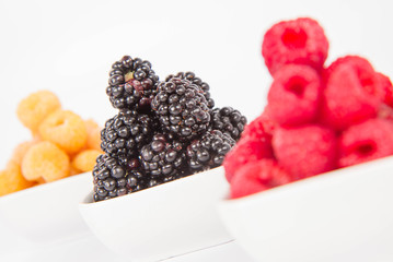 Raspberries and blackberries: bowls of fruit on white background