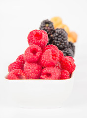 Raspberries and blackberries: bowls of fruit on white background