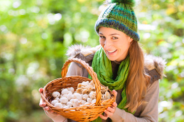 Frau mit Korb voller Pilze beim Sammeln im Wald