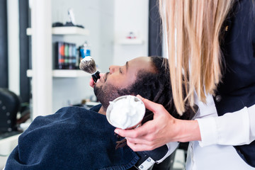 Barber soaping customer getting ready to shave him