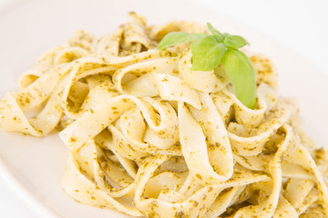 Tagliatelle with pesto decorated with basil on a white background