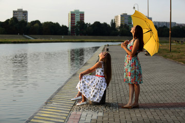 Matka i córka na wybrzeżu rzeki patrzą w niebo. - obrazy, fototapety, plakaty