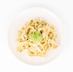 Tagliatelle with pesto decorated with basil on a wooden background