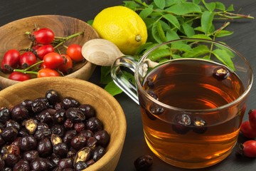 Drink from the hips in glass cup on wooden background. Traditional treatment of colds and flu. Medicinal plants.
