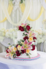 Beautiful white wedding cake with red roses as decoration. 