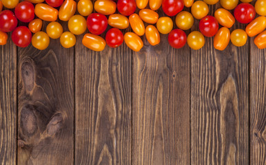 Cherry tomatoes harvest on wooden table background