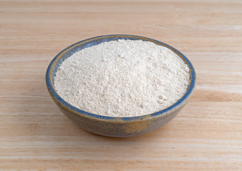 Quinoa flour in a bowl on a wood table.