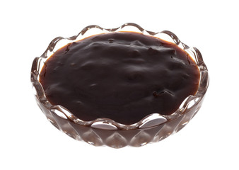 Glass bowl of plum preserves on a white background.