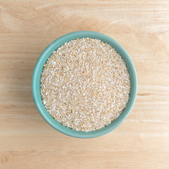 Dry oat bran hot cereal in a bowl atop a wood table.