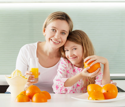 Mother and daughter make orange juice on a juicer