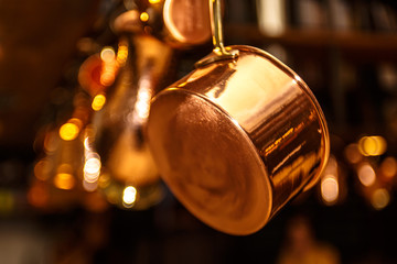 Copper kitchenware (pots, pans, jugs) hang from the ceiling in t