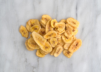 Dried bananas on a marble cutting board top view.