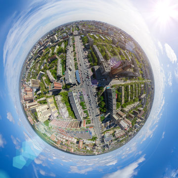Aerial city view with crossroads and roads, houses, buildings, parks and parking lots, bridges. Copter shot. Little planet mode. Full sphere.